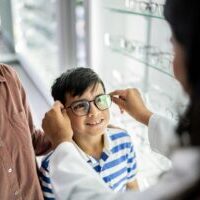 Child trying on glasses at optician