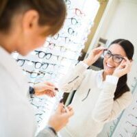 Woman trying on glasses at optician